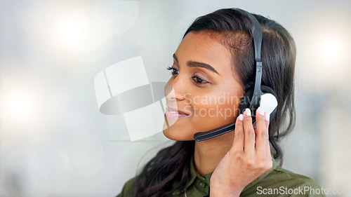 Image of Happy female customer service agent smiling while working in a call centre and talking to a client with a headset. A helpful saleswoman assisting customers with purchase orders and questions online