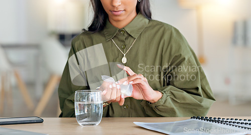 Image of Young woman taking medical drugs at home with a glass of water. Lady takes out the right amount of pills for her medication that was prescribed. Careful female giving herself treatment for relief.