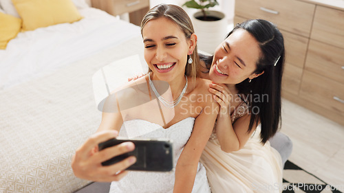 Image of Bride, bridesmaid and selfie with phone, wedding and ring with a smile to post on social media. Happy woman and asian friend excited for marriage celebration with fashion white dress in a bedroom