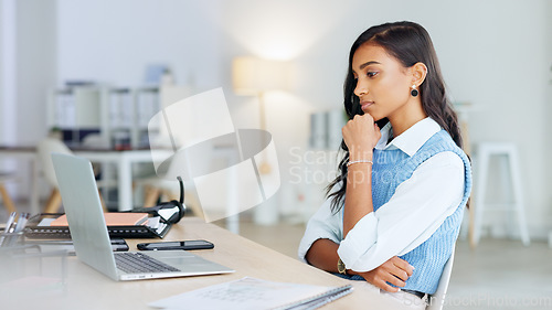 Image of Trendy business woman typing an email on a laptop and thinking while working on a project in her office. Young journalist or female entrepreneur working on blog and trying to find inspiration online