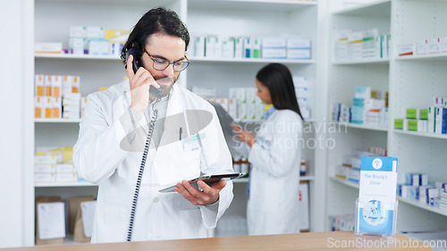 Image of Pharmacist man answering the telephone and giving advice to customer on flu shot treatment options in pharmacy. Chemist assisting remote client by checking medicine stock on tablet