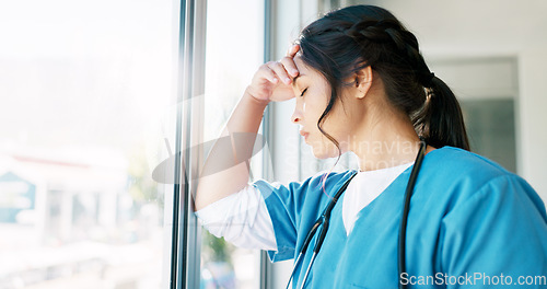 Image of Woman doctor, headache and burnout by window with stress, tired or sad in hospital workplace with pain in head. Professional medic, mental health problem and clinic with anxiety from healthcare job