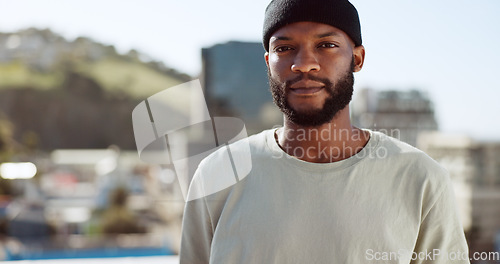 Image of Black man, serious and portrait on rooftop in city, wind or confident in summer on holiday. Young, man and buildings in urban, metro or town with proud, sunshine and beard with focus, vision or dream
