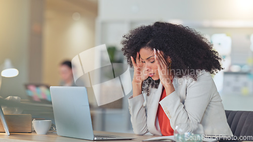 Image of Stressed software analyst typing on laptop with headache and making a mistake while analysing business or company data. Worried professional rubbing forehead with hands while struggling and pressured