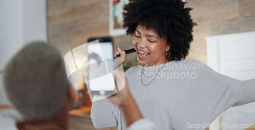 Image of Music, dance and singing with a phone in the hand of a woman for recording, fun or being playful. Joke, dancing and happy with an attractive young female enjoying free time and playing in a home