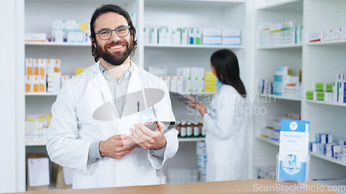 Image of Portrait of a cheerful and friendly pharmacist using a digital tablet to check inventory or online orders in a chemist. Young caucasian man using pharma app to do research on medication in a pharmacy