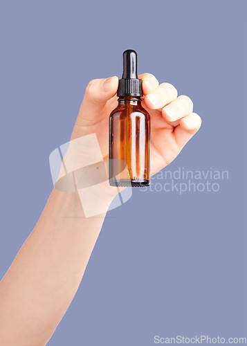 Image of Hands, skincare and serum bottle in studio isolated on a purple background. Product, dermatology and woman or female model with hyaluronic acid, essential oil or cosmetics for aesthetics and beauty.