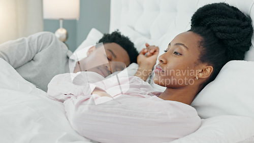 Image of Angry black woman in a home bedroom bed waiting for a tired sleeping man to wake up from sleep. African female ready to start an argument or fight feeling mad, moody or annoyed in house or apartment