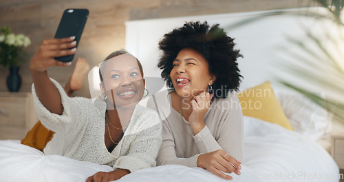Image of Happy, friends and selfie with phone in bed with a smile, relax and funny during a luxury vacation in a hotel room. African american women having fun with social media post on a 5g mobile smartphone