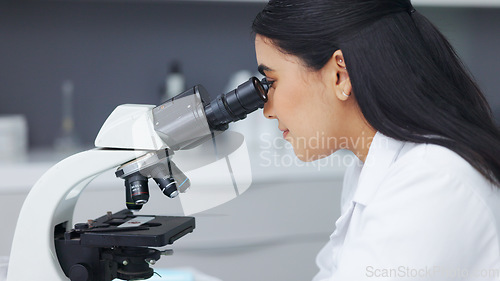 Image of Female scientist using a microscope in a research lab. Young biologist or biotechnology researcher working and analyzing microscopic samples with the latest laboratory tech equipment