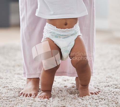 Image of Baby legs, learning and walking with mother, support and first steps of healthy body development. Closeup mom teaching child to walk, balance and feet on carpet for growth, milestone and motor skills