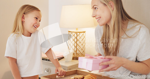 Image of Breakfast, child and mama with a gift on mothers day in the morning to celebrate her mommy at home. Smile, Love and happy girl giving parent a present box and a croissant with cookies in a bedroom