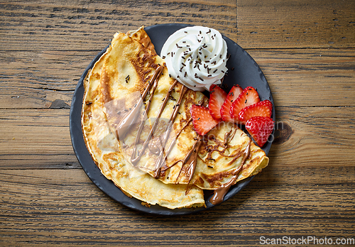 Image of freshly baked crepes with whipped cream and strawberries