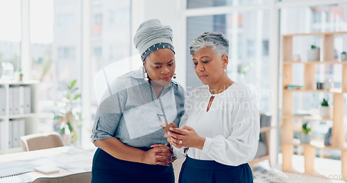 Image of Teamwork, discussion and business women with phone looking at report, project and business proposal online. Technology, communication and senior worker talking with smartphone to explain to coworker