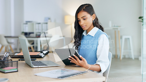 Image of Trendy marketing professional using an online app to network, meet deadlines and stay connected during office hours. Young business woman using her laptop and tablet while working in the office.