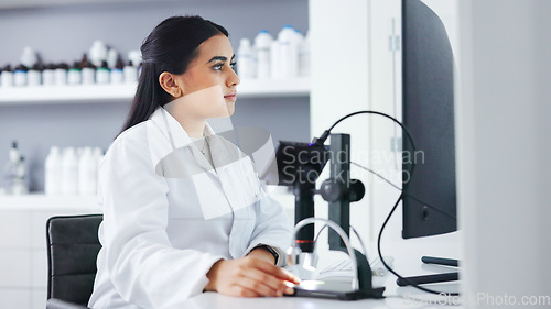 Image of Young scientist using a computer and microscope in a lab. Female pathologist analyzing medical samples while doing experiments to develop a cure. Microbiologist conducting forensic research