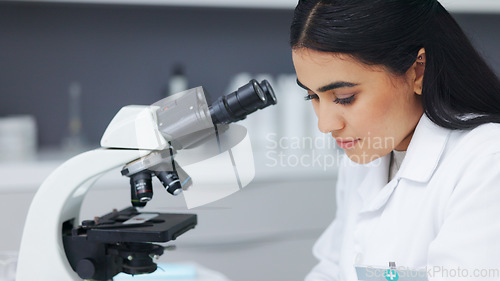 Image of Female scientist using a microscope in a research lab. Young biologist or biotechnology researcher working and analyzing microscopic samples with the latest laboratory tech equipment