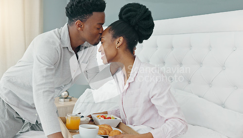 Image of Breakfast in bed, love and black couple being romantic on their honeymoon, birthday or anniversary in a hotel room. Happy man kissing woman on head to express love and care while bonding in bedroom