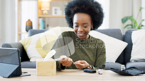 Image of Happy African American woman using a glucose monitoring device at home. Smiling black female checking her sugar level with a rapid test result kit, daily routine of diabetic care in a living room