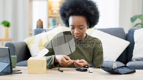 Image of Happy African American woman using a glucose monitoring device at home. Smiling black female checking her sugar level with a rapid test result kit, daily routine of diabetic care in a living room