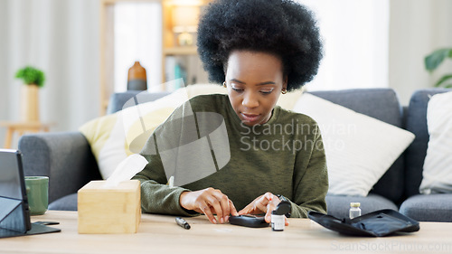 Image of Happy African American woman using a glucose monitoring device at home. Smiling black female checking her sugar level with a rapid test result kit, daily routine of diabetic care in a living room