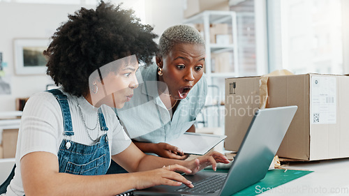 Image of Surprised, shocked and excited women looking amazed and showing happy expression sitting in their office. Two black professional entrepreneurs celebrating and cheering their new ecommerce business st