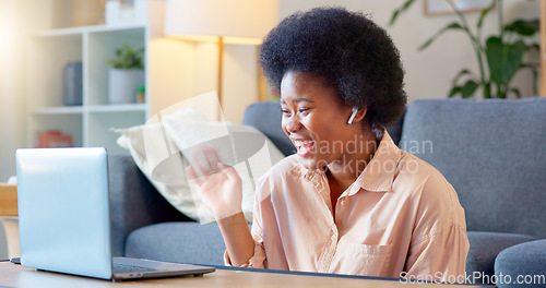 Image of Young woman on a video call on her laptop sitting at home home using her wireless headphones. Cheerful and beautiful African American female with afro talking to her friend online with a chat app