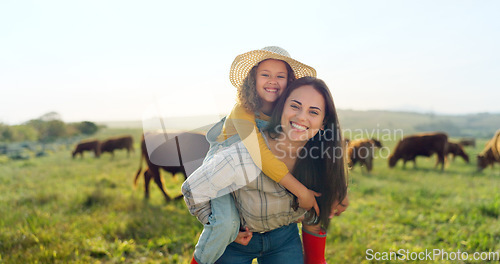 Image of Family, farm and fun with a girl and mother playing on a grass meadow or field with cattle in the background. Agriculture, sustainability and love with a woman and her daughter enjoying time together