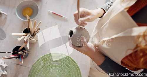 Image of Hands, pottery mud or sculpture artist with clay cup, mug or vase in art studio, product manufacturing workshop or small business. Top view, woman and sculpting tool in creative shop or ceramic class