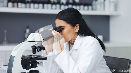 Image of Female scientist using a microscope in a research lab. Young biologist or biotechnology researcher working and analyzing microscopic samples with the latest laboratory tech equipment