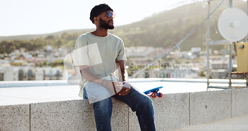 Image of Black man, relax and rest on wall with skateboard on building rooftop in city. calm, serene and young happy trendy skater guy with phone chill freedom adventure outdoors in bokeh town background