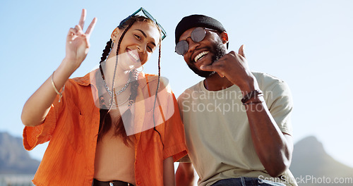 Image of Peace, love and couple in the city to relax, smile and be happy together in summer. Portrait of an urban and interracial man and woman with hand sign for communication and comedy against a blue sky