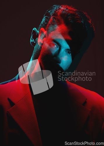 Image of Art, neon light blur and portrait of man with reflection of lights in eyes in with serious expression on face. Futuristic fashion, male model and beauty with red and blue on dark studio background.