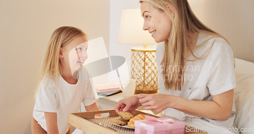 Image of Breakfast, child and mama with a gift on mothers day in the morning to celebrate her mommy at home. Smile, Love and happy girl giving parent a present box and a croissant with cookies in a bedroom