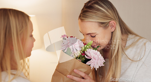 Image of Flowers, gift and happy with mother and girl for mothers day, birthday or congratulations in family home. Gratitude, smile and love with child giving bouquet to mom for present and celebration