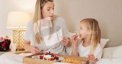 Image of Mother, child and breakfast in the bed of their house together in the morning. Girl relax, calm and in peace while talking and eating food on mothers day with her mom in the bedroom of their home