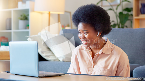 Image of Young woman on a video call on her laptop sitting at home home using her wireless headphones. Cheerful and beautiful African American female with afro talking to her friend online with a chat app