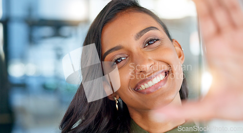 Image of Face of a happy business woman smiling, making funny expressions and creating a frame with her hand while standing in an office at work. Portrait of a smiling, carefree and cheerful female having fun