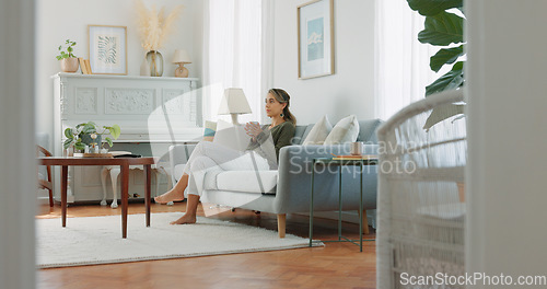 Image of Carefree woman drinking coffee and feeling relaxed and refreshed while relaxing on the couch at home. Female taking deep breath and smelling the aroma of a hot beverage, feeling mindful and content