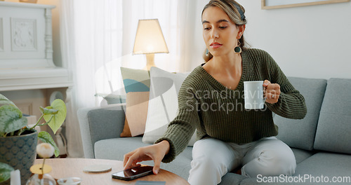 Image of Carefree woman drinking coffee and feeling relaxed and refreshed while relaxing on the couch at home. Female taking deep breath and smelling the aroma of a hot beverage, feeling mindful and content