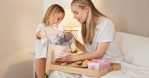 Image of Breakfast, child and mama with a gift on mothers day in the morning to celebrate her mommy at home. Smile, Love and happy girl giving parent a present box and a croissant with cookies in a bedroom