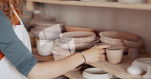 Image of Pottery woman, shelf and creative ceramic cups with artist or craft person standing in artisan workshop or art studio. Entrepreneur potter female enjoy hobby making art to sell in startup business