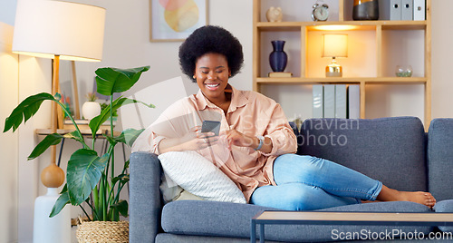Image of Laughing woman listening to music and sending a message with funny memes on her phone and drinking coffee while on the sofa. Happy black female browsing social media and surfing the internet online