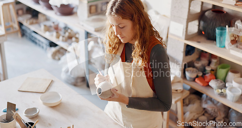 Image of Pottery, art and design woman artist in a home studio working on creative work. Ceramic arts designer or student at a learning workshop or house preparing a clay stencil pattern on a vase project