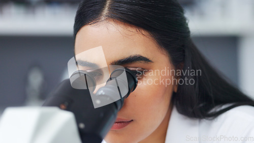 Image of Female scientist using a microscope in a research lab. Young biologist or biotechnology researcher working and analyzing microscopic samples with the latest laboratory tech equipment
