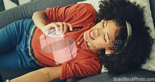 Image of Phone, music and singing with a black woman lying on a sofa in her home on the weekend from above. Mobile, karaoke and dance with a young female having fun alone in the living room of her house