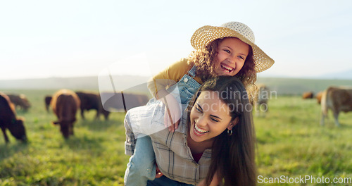 Image of Family, farm and fun with a girl and mother playing on a grass meadow or field with cattle in the background. Agriculture, sustainability and love with a woman and her daughter enjoying time together