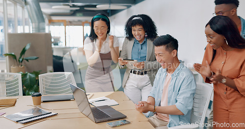 Image of Winner, yes and applause with a business asian man cheering with his team while working on a laptop on his office. Goal, wow and success with a male employee and colleague group in celebration