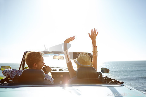 Image of Car, road trip and travel with a couple by the beach on a drive to enjoy the view during summer together. Freedom, transport and driver with a woman sitting hands raised by the ocean with her man