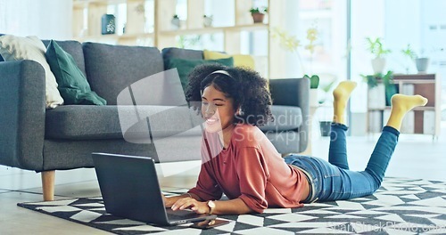 Image of Music, laptop and relax girl on floor carpet streaming radio rap, disco or rock song while singing trendy audio. Headphones, energy or student black woman listening to wellness sound and typing on pc